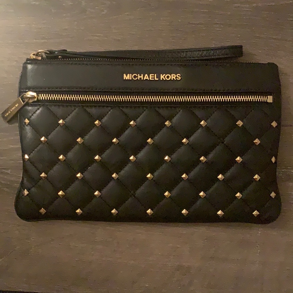 Black MICHAEL KORS wristlet. Gently used. Missing one gold piece at the bottom.